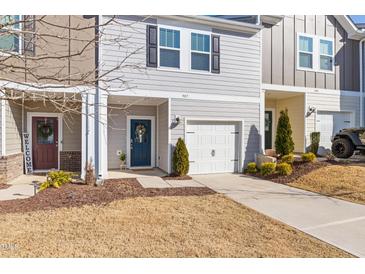 Charming gray two-story townhome with a one-car garage and a welcoming blue front door with seasonal wreath at 907 Field Ivy Dr, Fuquay Varina, NC 27526