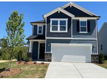 Charming two-story home showcasing a clean white garage door and complemented by tastefully dark blue siding at 106 Little Creek Dr, Lillington, NC 27546