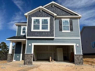 Charming two-story home with gray siding, shingle details, and attached two-car garage at 106 Little Creek Dr, Lillington, NC 27546