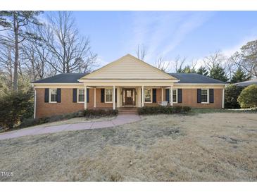 Charming brick home with a cozy front porch and a well-manicured lawn at 1401 Granada Dr, Raleigh, NC 27612