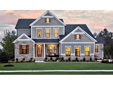 Stunning two-story home featuring a stone facade, covered porch, and professionally landscaped front yard at 1964 Old Byre Way, Apex, NC 27502