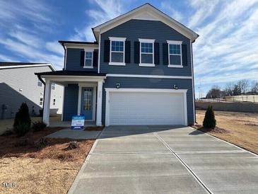 Charming two-story home with blue siding, black shutters, and a two-car garage at 223 Little Crk Dr, Lillington, NC 27546