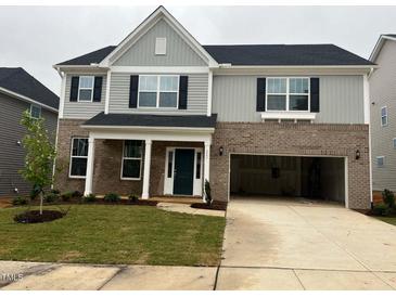 Two-story home featuring a brick and gray siding exterior, black shutters, and a two-car garage at 322 Oak Branch Trl, Garner, NC 27529