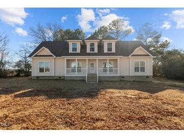 Charming home featuring a welcoming front porch and dormer windows under a blue sky at 406 Stewart Town Rd, Lillington, NC 27546