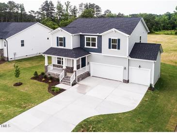 Two-story home showcasing well-manicured lawn, two-car garage, welcoming front porch, and stylish architectural details at 456 Barbour Farm Ln, Four Oaks, NC 27524