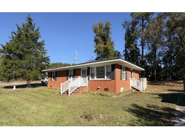 Charming brick home featuring a well-manicured lawn and bright white trim at 702 Joyner St, Clayton, NC 27520
