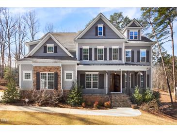 Charming two-story home featuring stone and shingle accents, complemented by a well-manicured lawn and landscaped garden at 198 Gentry Dr, Pittsboro, NC 27312