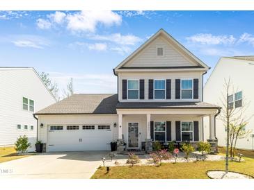 Charming two-story home with a well-manicured lawn and inviting front porch seating area at 1311 Arena Ln, Fuquay Varina, NC 27526