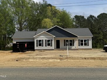 Charming one-story home featuring gray siding, black shutters, and a shingled roof in a serene, wooded setting at 327 S Main St, Four Oaks, NC 27524