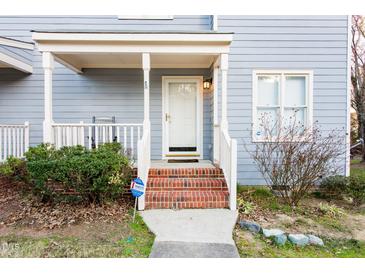Charming home featuring a cozy front porch with brick steps and manicured landscaping at 1620 Oakland Hills Way, Raleigh, NC 27604