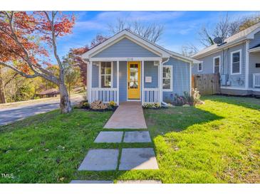 Charming blue home with a bright yellow front door and a walkway leading to the porch at 518 Worth St, Raleigh, NC 27601