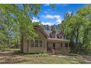 Rustic cabin-style home with a cozy front porch and lush green surroundings, perfect for peaceful living at 1031 Wait Ave, Wake Forest, NC 27587