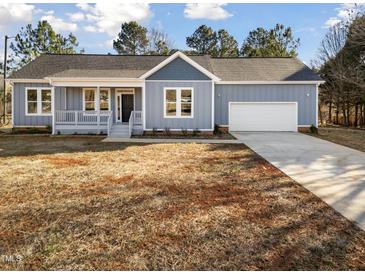 Charming single-story home with blue siding, a garage, a covered porch, and a well-manicured front yard at 1915 Lambert Rd, Graham, NC 27253