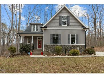 Charming two-story home with gray siding, stone accents, and a welcoming red front door at 2482 Golden Forest Dr, Franklinton, NC 27525