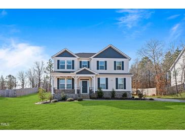 Two-story home features a manicured lawn, neutral siding, and a covered front porch at 594 Executive Dr, Lillington, NC 27546
