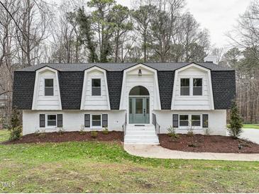 Charming two-story home featuring a symmetrical facade, black roof, and white brick exterior at 109 Chatterson Dr, Raleigh, NC 27615