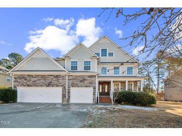 Charming two-story home featuring a stone facade, three-car garage, and inviting front porch at 309 Malvern Hill Ln, Morrisville, NC 27560