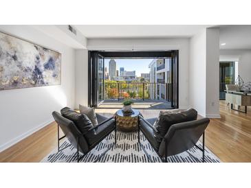 Bright living room featuring two leather chairs, an area rug, and balcony access with city views at 523 S West St # 502, Raleigh, NC 27601