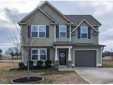 Inviting two-story home featuring a well-manicured lawn, attached garage, and charming architectural details at 258 Denning Farms Ln, Benson, NC 27504