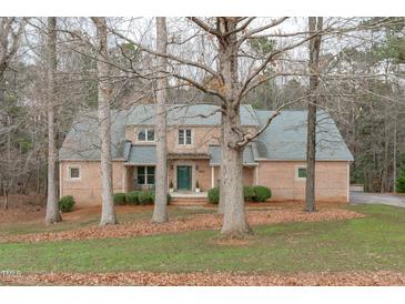 Charming brick home with a lush front lawn and mature trees providing shade and character at 5512 Spring Bluffs Ln, Raleigh, NC 27606