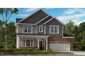 Charming two-story home featuring a brick facade, gray siding, and a welcoming front porch at 101 Hiddenite Pl, Holly Springs, NC 27540