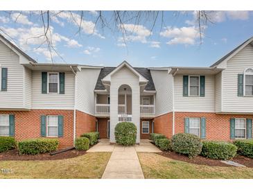 A charming townhouse with white siding, red brick accents, and manicured landscaping at 3322 Wellington Ridge Loop, Cary, NC 27518