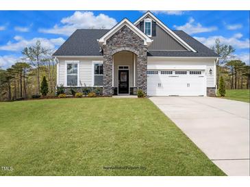 Beautiful home featuring a stone entryway, manicured lawn, and two-car garage at 15 Merle Dr, Wendell, NC 27591