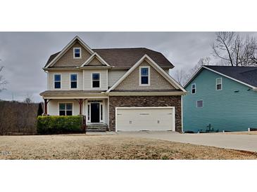 Two-story home featuring stone accents, attached two-car garage, and professionally landscaped front yard at 300 Nelson Ln, Clayton, NC 27527