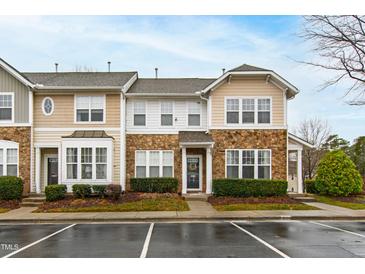 Charming townhome featuring stone accents, a landscaped front, and convenient parking at 5117 Singing Wind Dr, Raleigh, NC 27612