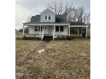 Quaint home featuring a covered porch and carport, set on a lot with mature trees at 728 East Ave, Henderson, NC 27536