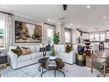 Bright living room featuring a comfortable white sofa, decorative pillows, and stylish decor, perfect for relaxation and entertaining at 810 Hyperion Aly, Wake Forest, NC 27587