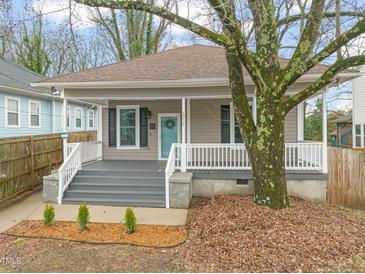 Charming home featuring a inviting front porch, landscaped yard, and mature tree at 1012 Holloway St, Durham, NC 27701