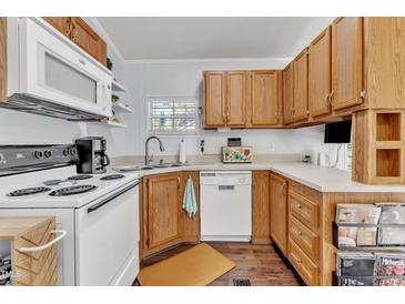 Cozy kitchen with oak cabinetry, white appliances, and a window above the sink at 104 Piquot Drive, Louisburg, NC 27549