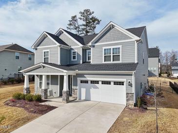 Charming two-story home features a gray exterior, covered porch, and a two-car garage at 1829 Knights Crest Way, Wake Forest, NC 27587