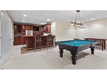 Finished basement featuring a bar with seating and a pool table for entertainment at 216 Copper Beech Ct, Chapel Hill, NC 27517