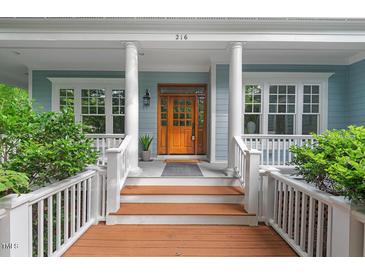 Inviting front entrance with a wooden door, white columns, and lush greenery enhancing its curb appeal at 216 Copper Beech Ct, Chapel Hill, NC 27517