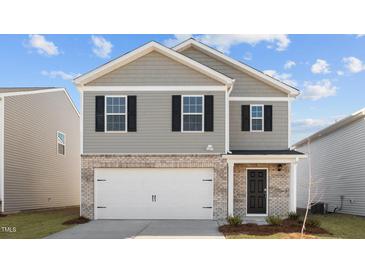 Two-story home featuring gray siding, brick accents, a white garage door, and black shutters at 258 Palm Dr, Sanford, NC 27332
