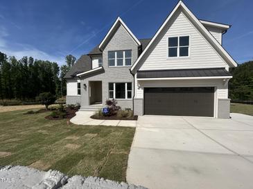 Charming two-story home featuring light gray brick, dark garage door and beautifully landscaped front yard at 5705 Flowery Meadow Ct, Wake Forest, NC 27587