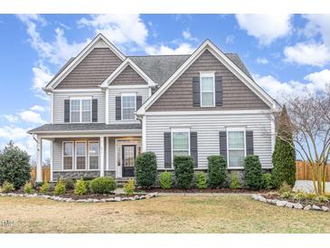 Charming two-story home with stone accents, dark shutters, manicured landscaping and covered entryway at 58 Atkins Village Ct, Fuquay Varina, NC 27526