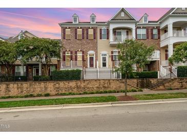 Beautiful townhome featuring brick facade, shutters, and white accents, plus manicured landscaping at 9221 Calabria Dr # 116, Raleigh, NC 27617