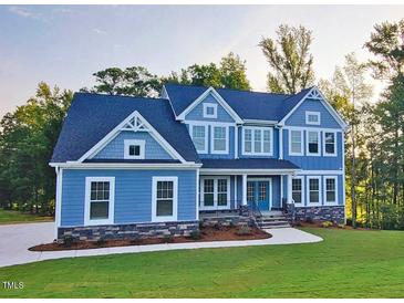 Beautiful two-story home featuring light blue siding and a meticulously manicured front yard at 9517 Wood River Dr, Zebulon, NC 27597