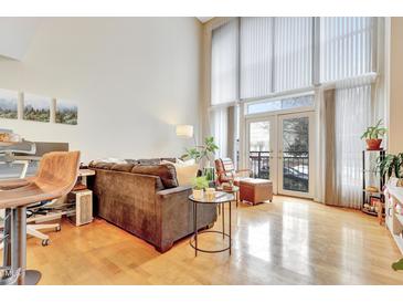 Bright living room with hardwood floors and a cozy seating area near the glass doors at 200 S Dawson St # 103, Raleigh, NC 27601