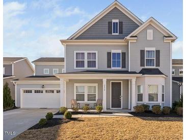 Charming two-story home featuring a gray color scheme, inviting front porch, and a convenient attached two-car garage at 2612 Nordmann Fir Rd, Raleigh, NC 27616