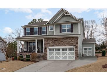 Charming two-story home with a stone facade, inviting porch, and a three-car garage, offering both elegance and practicality at 464 Granite Saddle Dr, Rolesville, NC 27571