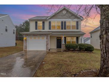 Charming two-story home featuring a stone-accented garage and manicured front yard at 702 Blue Lake Dr, Mebane, NC 27302
