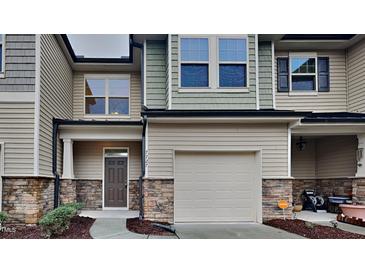 Inviting townhome with a well-manicured lawn, stone accents, and attached one car garage at 7727 Weathered Oak Way, Raleigh, NC 27616
