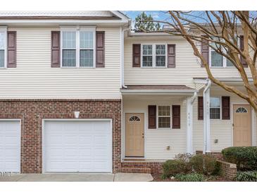 Two-story townhome with attached garage, brick facade, and light yellow vinyl siding at 4618 Pooh Corner Dr, Raleigh, NC 27616