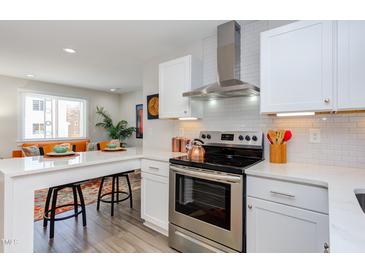 Modern kitchen with stainless steel appliances, white cabinetry, and an eat-in island at 1309 Hudson Ave # D8, Durham, NC 27705