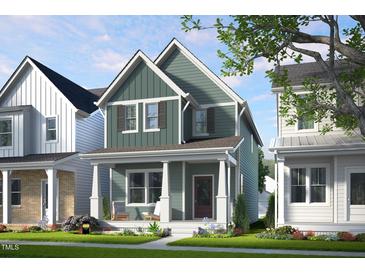 Charming two-story home showcasing a covered front porch, manicured lawn, and vibrant landscaping at 1905 Plott Balsam Dr, Wendell, NC 27591