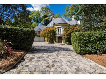 Elegant stone home features a turret entry, manicured landscaping, and a paver driveway at 2658 Davis St, Raleigh, NC 27608